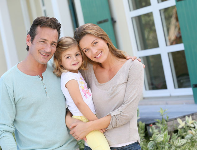 Smiling family outside their home.